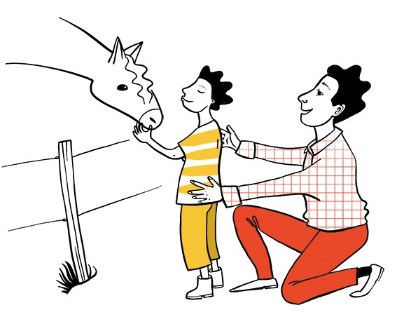 En pojke klappar mulen på en häst. Hans pappa står på knä oc hhåller sina händer på pojkens kropp.